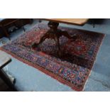 An early 20th century Persian Mahal rug with large central field motif on wine ground within rosette