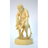 A Japanese ivory okimono of a standing artisan, holding a long-tailed ho-ho, or other, bird,