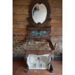 A Victorian cast iron console table with oval mirror above Art Nouveau style green ceramic tiles