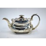A Regency silver half-reeded teapot of squat oblong form with foliate applied handle and spout,