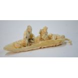 A sectional ivory carved as a Chinese scholar seated on a leaf-shaped vessel beside his two