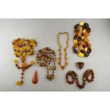 A collection of pressed amber glass and other beads of yellow and brown shades to/w a pendant and