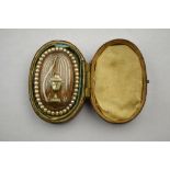 A Georgian oval mourning brooch featuring a mother of pearl urn beneath seed pearl set weeping