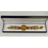 An 1864 Victorian bun head sovereign enclosed in ornate mount in centre of 9ct gate bracelet with