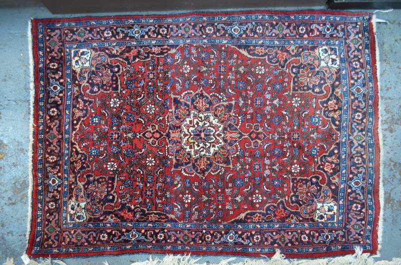 A fine Persian Bidjar rug with large central floral motif on red ground within multi-borders,