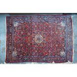 A fine Persian Bidjar rug with large central floral motif on red ground within multi-borders,