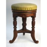 A late Victorian revolving piano stool with padded seat, on three swept supports