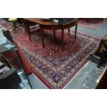A Persian Mashad carpet, the large central floral motif on wine ground with floral decoration and