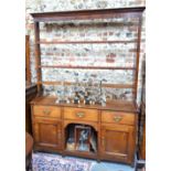 A George III oak high dresser, the open three tier rack over three frieze drawers and an open