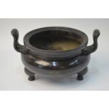 A Chinese bronze incense burner of circular form with two pierced handles and tripod feet;