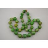 A single row of graduated green jade beads, graduated from 1.2 cm-0.8 cm knotted throughout onto
