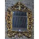 A giltwood wall mirror with shaped plate and foliate-carved and pierced frame,