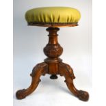 A Victorian carved walnut revolving piano stool with padded seat, on tripod base