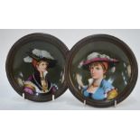 A pair of Berlin-style porcelain dishes with beaded copper rims, painted with finely-dressed ladies,