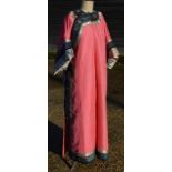 A long pink-ground Chinese textile costume with white fringes and sleeves;
