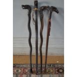 Three carved wood walking sticks with dragon's head handles and another stick carved as a cobra (4)