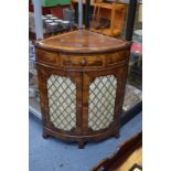 A laburnum-veneered corner cabinet with crossbanded top above bowfront drawer and two doors with