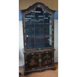 An ebonised and gilded display cabinet with astragal glazed door above two panelled doors decorated