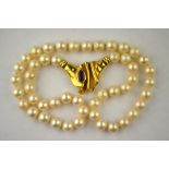 A single row of uniform cultured pearls having large 18ct yellow gold central snap set with