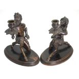 A companion pair of late 19th/20th century brown bronze patinated candelabra, cast as kneeling