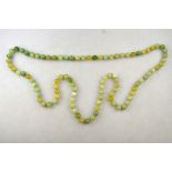 A long green-stone bead necklace, knotted throughout