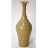 An olive green monochrome vase with trumpet neck and unglazed base,