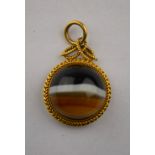 A Victorian circular banded agate cabochon pendant in yellow gold rope style setting with locket at