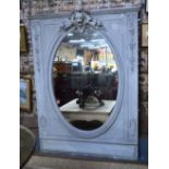 An antique French carved and moulded overmantel with oval mirror plate,