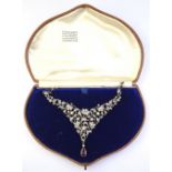 An Edwardian paste necklace of flower and leaf motif, set white paste with mauve paste drop,