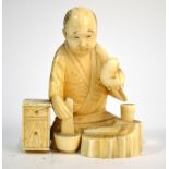 A small stained ivory, Japanese okimono, carved as a seated artisan,