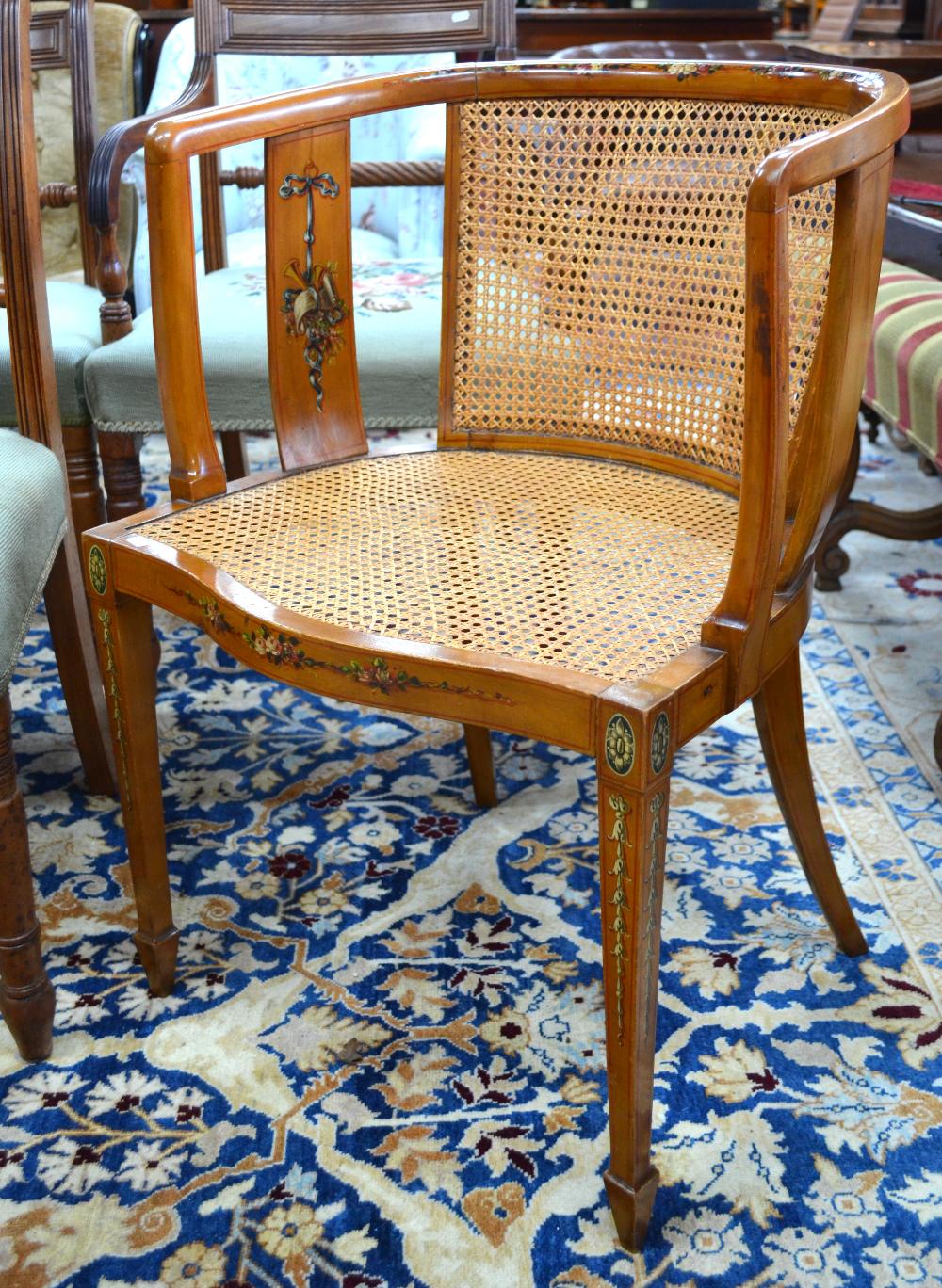 A Sheraton style caned satinwood chair with polychrome floral decoration and serpentine form seat,