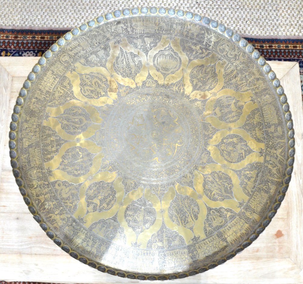 A finely engraved Asian brass tray with pictorial scenes raised on a fruitwood tripod base as a - Image 2 of 6