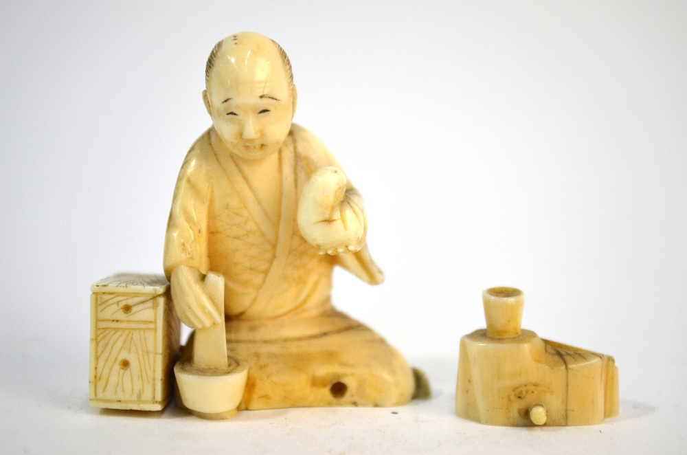 A small stained ivory, Japanese okimono, carved as a seated artisan, - Image 2 of 4