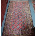 A Belouch rug, the three linked gul design on dark pink ground,