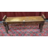 A Victorian oak window seat with bobbin turned arms to ends and raised on conforming legs,