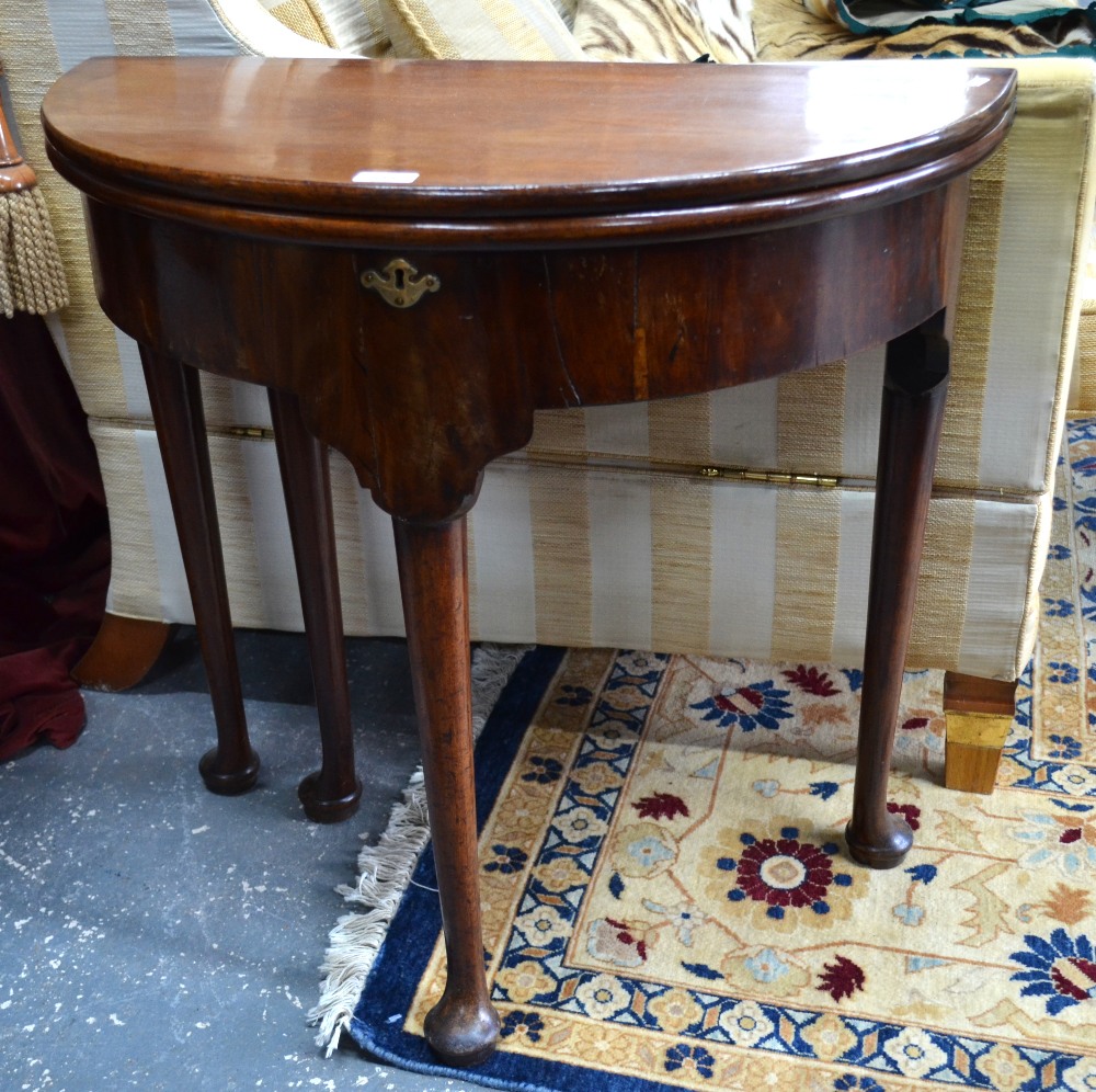 An 18th century mahogany demi-lune fold over gateleg table with storage well raised on four turned
