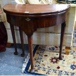 An 18th century mahogany demi-lune fold over gateleg table with storage well raised on four turned