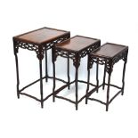 A nest of four Chinese hardwood graduated occasional tables each with pierced fret cut panels,