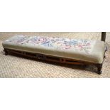 A Victorian rosewood framed long footstool with overstuffed floral needlepoint cover,