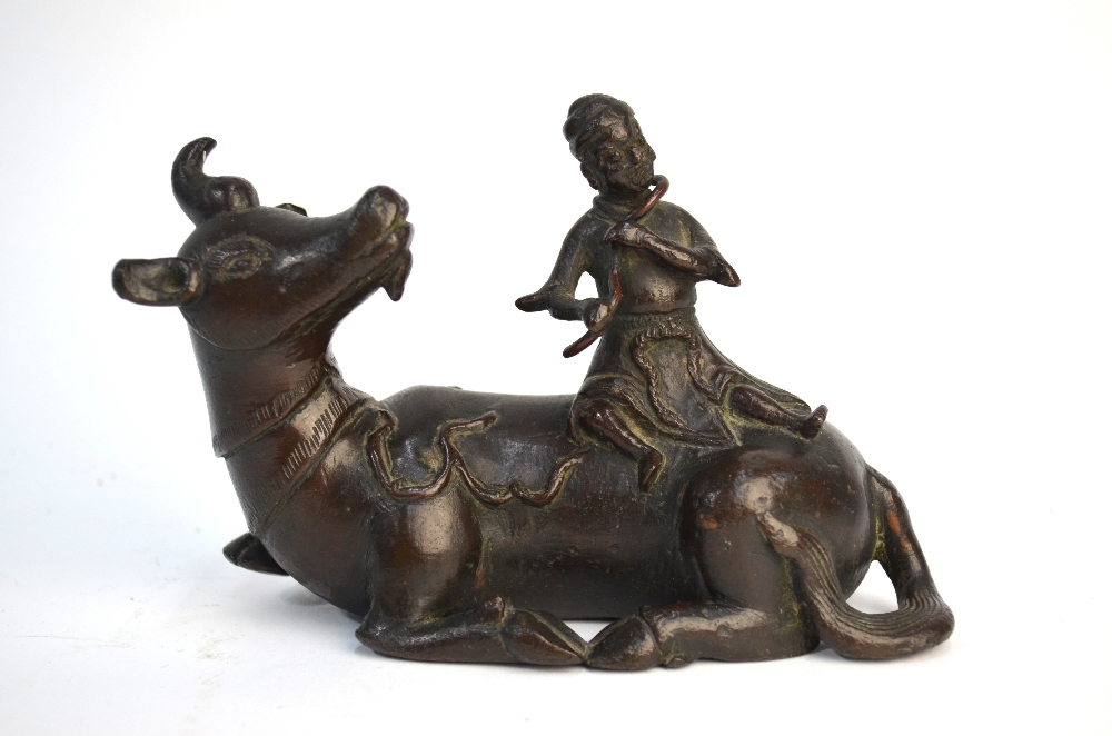A Chinese bronze figure of a scholar seated on a recumbent buffalo, possibly a mirror stand,