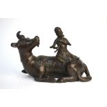 A Chinese bronze figure of a scholar seated on a recumbent buffalo, possibly a mirror stand,