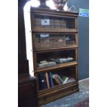 An oak Globe Wernicke four section bookcase over a plinth drawer