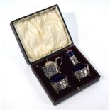 An Edwardian cased silver four piece condiment set with pierced sides and blue glass handles,
