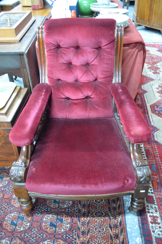 An open armchair with deep button red velveteen cover,