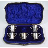 An Edwardian cased part set of five of silver two-handled shot cups as miniature loving cups,