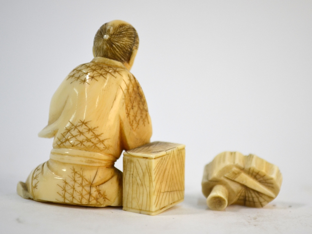 A small stained ivory, Japanese okimono, carved as a seated artisan, - Image 3 of 4