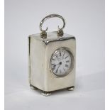 A late Victorian silver boudoir clock with scrolling loop handle and bun feet,