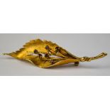 A 9ct yellow gold textured and pierced leaf brooch, having six claw set garnets forming seeds,