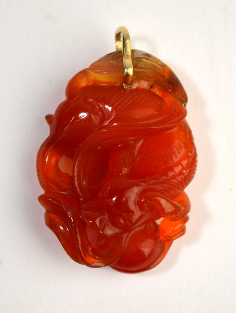 A mottled orange cornelian pendant with yellow metal ring,