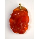 A mottled orange cornelian pendant with yellow metal ring,